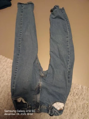 Slim fit jeans från H&M, blå - Blå jeans från H&M i slim fit-modell med justerbar midja. Klassisk femficksdesign och elastisk midja för extra komfort. Jeansen har raka ben och är tillverkade i mjukt denimtyg som passar perfekt till en avslappnad stil.