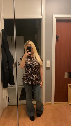 Leopardmönstrad blus i svart och beige i satin - Säljer en snygg blus med leopardmönster i svart och beige. Blusen har korta ärmar och rund hals, med en loose passform som ger en chill vibe. Materialet känns som mjuk polyester och toppen är perfekt för dig som gillar djurmönster och vill sticka ut.