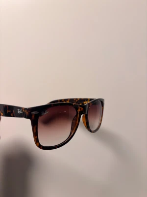 Ray ban wayfarer tortoise shell - Superfina solglasögon i tidlös wayfarer-stil. Bågarna har ett snyggt sköldpaddsmönster och linserna är lätt tonade (mörkare upptill, ljusare nedtill). Passar de flesta ansiktsformer och sitter bekvämt. Perfekta både till vardags och soliga dagar på resan! . Normal passform. I fint skick. Pris kan diskuteras. Skriv vid minsta fundering!