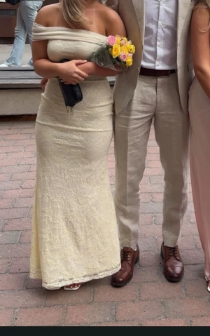 Ljusgul offshoulder balklänning - Ljusgul balklänning som blivit använd en gång endast, är 160cm och har låga klackskor i bilden för referens. Köpt på JJ house i storlek XS/S perfekt för balsäsongen som kommer 💛