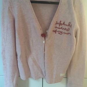 Ljusrosa kofta från Odd Molly - Superfin ljusrosa kofta från Odd Molly med broderad text på bröstet och snygga detaljer som dragkedja vid ärmslut och knappar framtill. Tillverkad i mjuk lammull och nylonblandning, perfekt för att ge din outfit en chill vibe. Har inte blivit använd här. Så Nyskick… men den är så fin. 