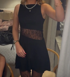 Svart klänning med spetsdetalj - Supersnygg svart kort klänning från Zara med transparent spetsband i midjan. Ärmlös modell med rund hals och lätt utställd kjol. Perfekt coktailklänning! Den är endast använd två gånger🥰