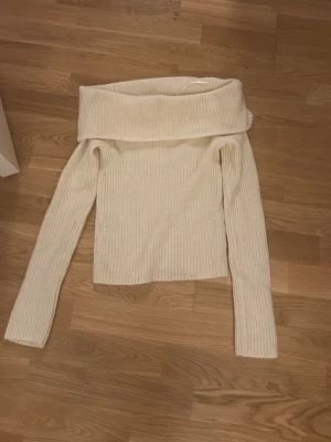 Offshoulder ribbad tröja från H&M - Superfin offshoulder tröja från H&M i ribbstickad, mjuk och krämvit kvalitet. Långärmad modell med bred krage som vilar snyggt över axlarna. Perfekt för dig som gillar en stilren och trendig look.