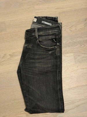 Replay Anbass  - Snygga Replay Anbass jeans i grå/svart färg. W30 L32. Modellen kallas fär aged 05 anbass. Klassisk femficksmodell med Replay-logga på fickan och svart läderpatch bak i midjan. Slim fit och töjbar.