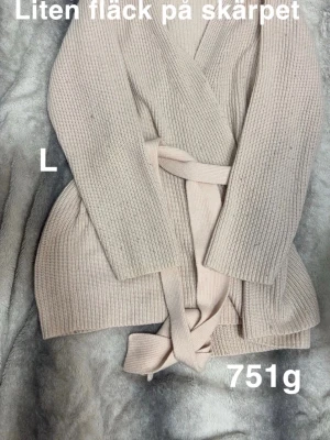 Rosa stickad kofta med bälte L - Mysig rosa stickad kofta i storlek L med omlott-design och matchande bälte i midjan. Koftan har långa ärmar och ribbad struktur som ger en snygg och avslappnad look. Perfekt för lager-på-lager under kyliga dagar.🌸 Noppor. Öglan som skärpet har släppt på ena sidan. Liten fläck på skärpet. Skärpet är mer rosa än koftan. Storlek L