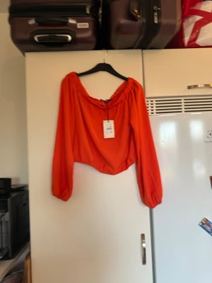 Orange topp - Säljer en otroligt snygg orange långärmad topp i storlek L. Helt ny med tags/ prislapp fortfarande kvar. 