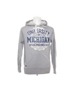 Grå hoodie University of Michigan - Grå hoodie från American Freshman med stor blå University of Michigan-print på bröstet. Tröjan har huva med snörning, mjukt foder och klassisk känguruficka framtill. Perfekt för dig som gillar college-vibe och sportig stil.