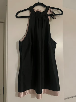 Satin topp - Festtopp med knyte i nacken, en längre modell med dubbelt material (rosa på insidan och svart på utsidan) går att använda den ut och in. 
