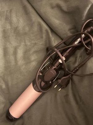 Babyliss locktång svart/rosa - Snygg locktång från Babyliss med svart handtag och rosa cylinder. Perfekt för att skapa mjuka lockar och vågor. Utrustad med sladd och EU-kontakt, enkel att använda och passar de flesta hårtyper.