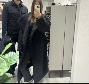 Gina Jacka - Säljer en svart lång teddyjacka med oversized passform och bred krage. Jackan har en mysig, fluffig textur och är perfekt för kalla dagar. Enkel att styla till både jeans och sneakers för en chill look.