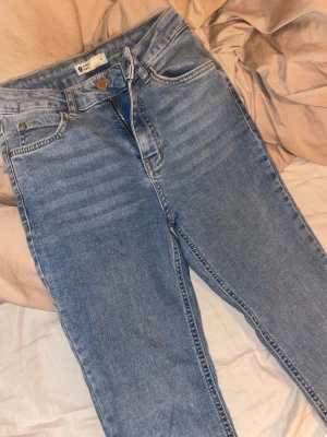 Blå bootcut jeans från Gina tricot  - Snygga ljusblå jeans från Gina tricot i storlek S. Modellen har klassisk femficksdesign, dragkedja och knapp framtill. Jeansen har bootcut-ben och är tillverkade i mjukt denimtyg som sitter skönt. Perfekt för dig som gillar retrovibbar och avslappnad stil.