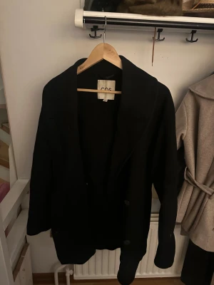 Svart kort kappa COS - Svart kort kappa med knappar från COS, bra skick, nypris 1499kr🙌🏽Storlek Xs, men sitter som S/M. BUDA PÅ!!