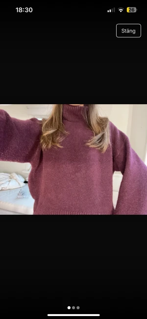 Vinröd polotröja i stickad ull - Mysig vinröd polotröja med hög krage och långärmad modell. Tröjan är stickad i ull och har en loose passform med ribbade muddar vid hals, ärmslut och nederkant. Perfekt för kalla dagar och enkel att styla med jeans eller kjol.