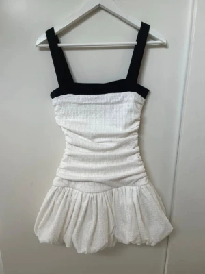 Vit och svart kort klänning från Zara - Supersöt kort klänning från Zara i vit med svarta breda band, den har också en dragkedja i sidan för enkel påklädning. Aldrig använd med prislapp kvar. Säljer då jag inte hann lämna tillbaka den i tid. 