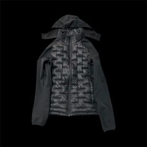 Svart pufferjacka med huva - Svart pufferjacka med quiltad front och rygg, släta ärmar och avtagbar huva. Jackan har dragkedja framtill och en stilren look som passar perfekt till höst och vinter. Materialmix med glansig polyester på kroppen och matta ärmar.