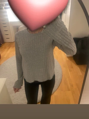 Stickad tröja  - Säljer en grå långärmad tröja från Amisu i storlek S. Tröjan har ett ribbat mönster och är tillverkad i mjuk bomullsmix. Rund halsringning och vågig kant vid ärmslut och nederkant ger en chill vibe. Perfekt att matcha med jeans eller leggings.