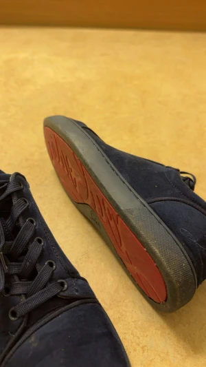 Mörkblå Loubs - Snygga mörkblå sneakers i mocka med platt sula och rund tå. Skorna har svarta snören och en cool röd undersida på sulan. Perfekt för dig som gillar stilrena och klassiska sneakers med en twist. Passar till jeans och hoodie eller en mer dressad look. Tar helst byten emot jacka annars säljes, kartong osv finns kvar, skriv för fler bilder eller för frågor!