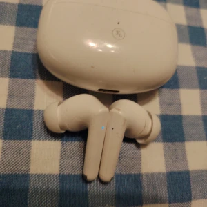 FL True Wireless Pro Hörlurar med buetooth, docka och USB-C laddning - Vita trådlösa hörlurar med sjukt bra bas för pengarna samt tillhörande laddningsetui, USB-C-kabel för laddning och helt nya plastkuddar för en fräsch lyssnarupplevelse. Finns ett litet märke på dockan annars i utmärkt skick. Perfekt för dig som söker prisvärda hörlurar för vardagsbruk. 