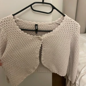 Beige stickad kofta med blomknapp - Supersöt beige stickad kofta från Flash med trekvartsärm och rundad kant. Koftan har en unik blomformad knapp framtill och fina virkade detaljer längs kanterna. Perfekt att slänga över ett linne för en chill och söt look. Den är i storlek M men passar mig som har S!🥰🥰