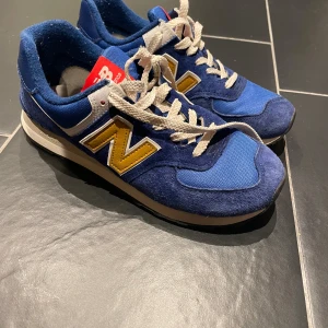 Blå New Balance 574 sneakers - Hej! Säljer ett par new balance sneakers, storlek 41,5 26cm. Fint skick, sparsamt använda, endast lite noppor på insida häl kappa. 