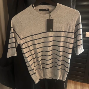 Grå randig tröja från lager 157 - Snygg grå tröja från lager 157 i storlek XS med mörkblåa ränder. Tröjan är aldrig använd utan enbart testad så i nyskick. Perfekt för dig som gillar en stilren och enkel look.
