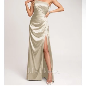 Champagnefärgad lång klänning  - Elegant långklänning i champagnefärgad satin från JJ's House. Klänningen har en axelbandslös design med draperad överdel och hög slits. Själv är jag 155 cm lång