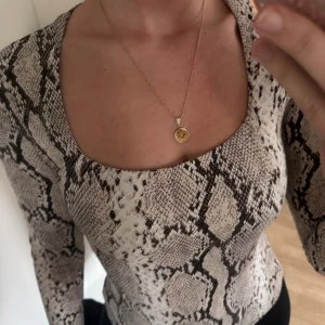 Långärmad topp med ormmönster H&M - Säljer en långärmad topp från H&M med snyggt ormmönster i beige, svart och grå toner. Toppen har fyrkantig ringning och är figurnära i modellen. Perfekt att styla med jeans eller kjol för en trendig look.