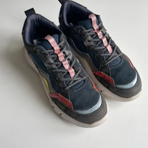 Chunky sneakers från Zara i färgblock - Feta sneakers från Zara med cool färgblock-design i svart, blått, rött, gult och grått. Ovandel i mocka och textil, detaljer i syntet och mesh. Tjock vit sula och snörning med rosa och gråa skosnören. Perfekta för dig som gillar statement-skor.