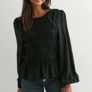 Svart blus med volang - Säljer en svart blus med rund hals och långa puffiga ärmar. Toppen har smockad front och volang nedtill som ger en snygg siluett. Perfekt att styla med jeans eller kjol för en cool look. Materialet känns lätt.