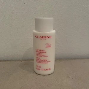 Clarins Velvet Cleansing Milk 100ml - Clarins Velvet Cleansing Milk i vit plastflaska, 100 ml. Rengöringsmjölk med extrakt av alp-gentiana och citronmeliss. Passar alla hudtyper och har en mjuk, krämig konsistens. Perfekt för att ta bort smink och fräscha upp huden.