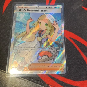 Lillie's Determination -  Full art kort!!!!!! Cool och glittrig Pokémon-samlarbild med Lillie, perfekt för dig som älskar att spela och samla Pokémonkort! Kortet har snygg design och är ett supporter-kort som kan ge dig fördelar i spelet. Ett måste för unga Pokémon-fans och samlare!