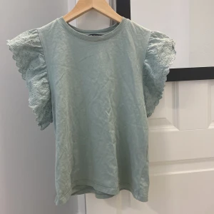 Ljusgrön blus med volangärmar från Zara - Supersöt ljusgrön blus från Zara med volangärmar. Rund halsringning och rak passform. 