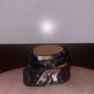 Fint färgglatt skärp bälte - Säljer ett bälte med svart spänne och färgstarkt camouflage-mönster i svart, vitt, grönt, lila, gult och rosa. Bältet är gjort i skinn och har en exklusiv känsla med sin unika design och klassiska logga framtill. Mer bilder via dm👍