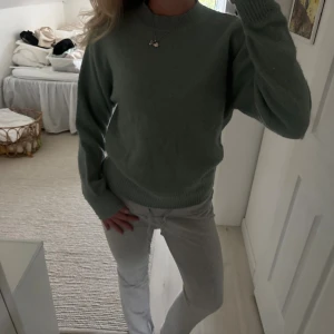 Grön stickad tröja med rund hals - Mysig grön stickad tröja med rund halsringning och ribbade muddar vid ärmslut och nederkant. Perfekt för lager-på-lager och passar till både jeans och mjukisbyxor. Enkel och stilren design som funkar året runt.