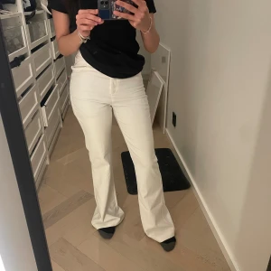 Vita bootcut byxor från Bershka - Säljer ett par snygga vita bootcut-byxor från Bershka. De har hög midja, klassisk femficksdesign och dragkedja fram. Det är ett par kostymbyxor med lite stretch för extra komfort. Perfekta för dig som gillar en stilren och trendig look.