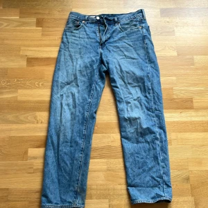 Levi's  blå jeans straight fit - Klassiska blå Levi's  jeans med rak passform och fem fickor. Jeansen har den ikoniska läderpatchen bak i midjan och röd Levi's-tag på bakfickan. Tillverkade i slitstarkt bomullsjeans, perfekt för en avslappnad och tidlös look.