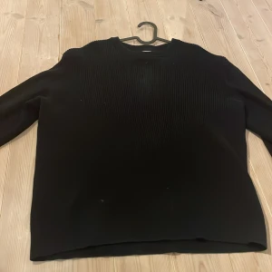 Svart långärmad tröja  - Svart långärmad tröja från H&M med relaxed fit. Tröjan har ett ribbat mönster över hela ytan och rund halsringning. Perfekt för dig som gillar en enkel men ändå stilren look.