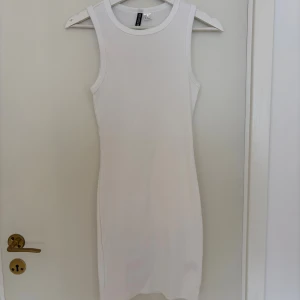 Vit ribbad klänning från H&M Divided - Säljer en vit, tight klänning ifrån H&M i storlek S. Aldrig använd.