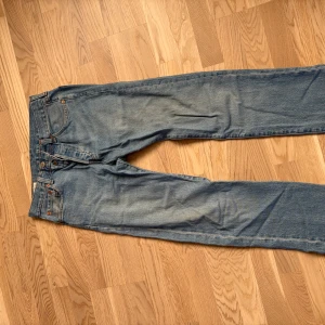 Levi's 501 ljusblå jeans W29 L32 - Klassiska Levi's 501 jeans i ljusblå tvätt med raka ben och knappgylf. Jeansen har fem fickor, orange sömmar och den ikoniska läderpatchen bak. Perfekta för dig som gillar en tidlös och avslappnad look.