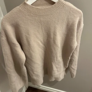 Beige stickad tröja med slits  - Beige stickad tröja med låg polo och slits på båda sidor. Aldrig använd