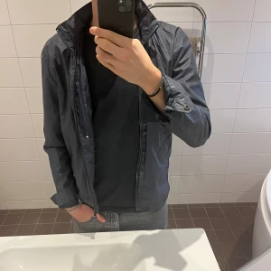 Mörkblå vindjacka från Samsøe Samsøe - Mörkblå jacka från Samsøe Samsøe med hög krage och dragkedja framtill. En modern jacka som är riktigt snygg och väldigt bra kvalité. Passar perfekt till både hösten och våren. 