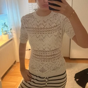 Vit stickad kortärmad tröja - Säljer en vit stickad tröja med korta ärmar och snyggt hålmönster. Använd få gånger så bra skick! 