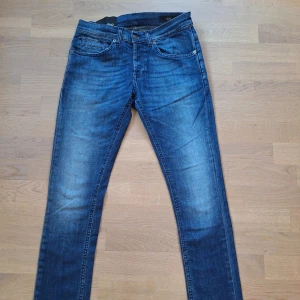 Blå skinny jeans från Dondup - Snygga blå jeans från Dondup i skinny fit, modellen George, med klassisk femficksdesign och coola slitningar. Jeansen har låg midja, knappgylf samt broderade detaljer på bakfickorna. Small passform. Perfekt för dig som gillar en skinny jeans!. Tillverkad i Italien. 