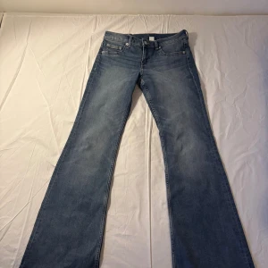 Blå flare jeans från H&M Divided - Säljer ett par blå flare jeans från H&M Divided i storlek 38. De har låg midja och klassisk femficksdesign. Jeansen är tillverkade i denim och har en snygg utsvängd passform nertill för en trendig look.