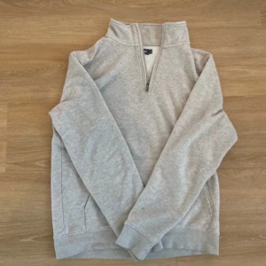 Beige half zip sweatshirt Dressmann - Beige sweatshirt från Dressmann med half zip-dragkedja och hög krage. Tröjan har långa ärmar, ribbade muddar och fickor i sidorna. Perfekt för lager-på-lager och chill dagar.