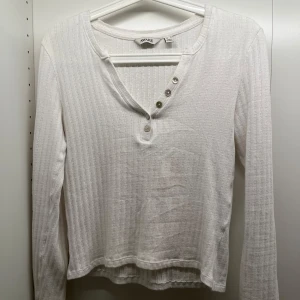 Vit långärmad topp - Säljer en vit långärmad topp i bra skick. Tröjan har en snygg knappdetalj vid halsringningen och perfekt till vardag. Säljer då den är för liten för mig.