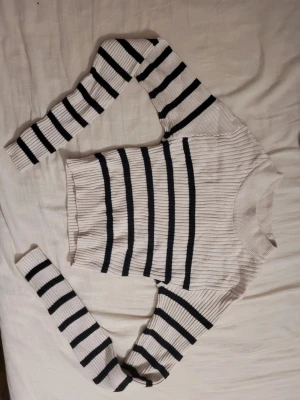 Randig ribbad tröja i vitt och svart - Säljer en ribbad tröja med svartvita ränder. Tröjan har lång ärm och en klassisk rund halsringning. Perfekt för dig som gillar en enkel men ändå stilren look. Materialet känns mjukt och stretchigt, vilket gör den skön att bära.