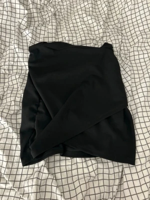 Svart omlottkjol från SHEIN - Snygg svart kortkjol från SHEIN i omlottmodell. Kjolen har en diskret dragkedja bak och är gjord i ett mjukt, lätt stretchigt material som sitter bekvämt. Enkel och stilren design som är lätt att matcha med olika toppar.