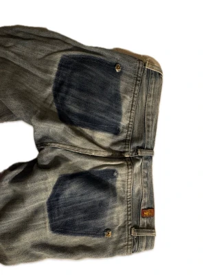 Blå bootcut jeans från 7 For All Mankind - Pris kan diskuteras!! Säljer ett par blå bootcut jeans från 7 For All Mankind med slitningar och hål på ena benet🩷 Jeansen har klassiska fem fickor, låg midja och snygg tvätt med kontrasterande bakfickor. Perfekta för dig som gillar en avslappnad och trendig look. De har tyvärr lite slitningar vid fötterna och dessutom ett trasigt hål för bälteshållare men de verkar ganska lätt att laga🩷