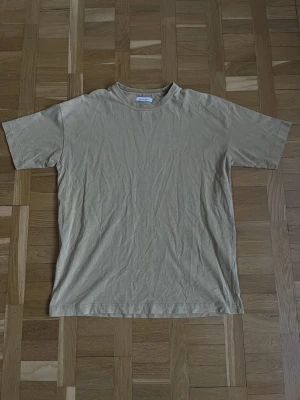 Beige t-shirt från Samsøe Samsøe - Enkel beige t-shirt från Samsøe Samsøe i mjuk bomull. Klassisk rund halsringning och korta ärmar. Perfekt basplagg som funkar till allt och har en clean look.
